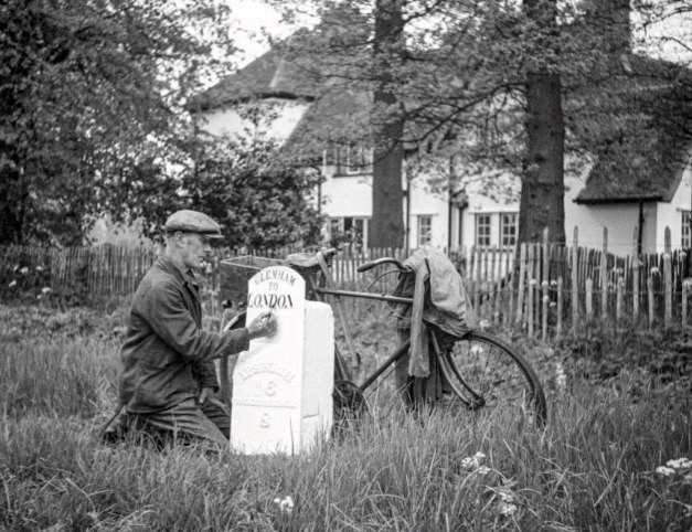 black and white photo of a man painting the mile post